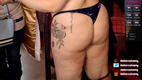 Media: Video of a woman with light skin, wearing a navy thong, showing off a large octopus tattoo on her left buttock. Background includes a wooden door, dim lighting, and a Twitter icon.
