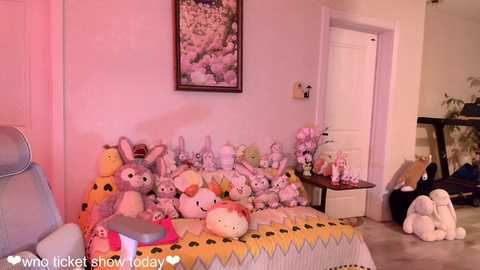 Media: A video of a cozy living room with a yellow-striped couch adorned with plush animal toys, including rabbits, a dog, and a frog, against a pink wall.