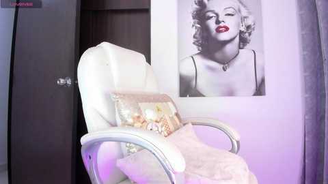 Media: Video of a modern, minimalist bedroom featuring a white leather recliner chair with a floral pillow, adorned with Marilyn Monroe's iconic black-and-white portrait on the wall.
