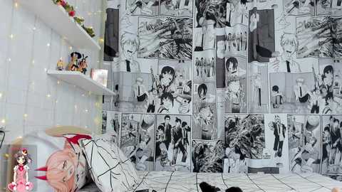 Media: Video of a young person lying on a bed with a black-and-white manga-style wallpaper, featuring various characters. The person has pink hair, and the room is cozy with fairy lights and a doll collection on a shelf.