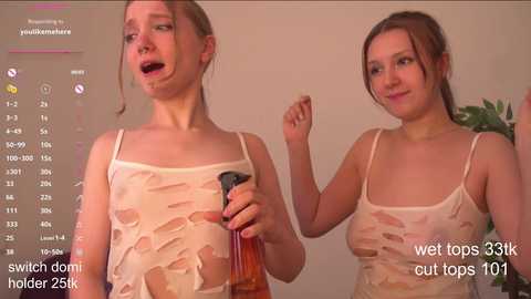 Media: Video of two young women with light skin, wearing see-through wet tops, holding bottles of water. One looks surprised, the other smiling. Background shows a bathroom with a plant.