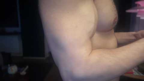 Media: A close-up video of a pale-skinned, topless individual with medium-sized breasts and visible nipples, taken indoors with a blurred background.