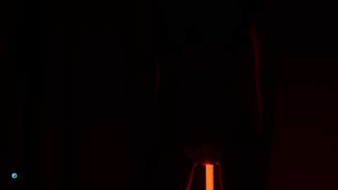 Media: A dimly lit, abstract video featuring a red and black gradient background with a faint, glowing, orange-red light source in the lower right corner. The image is dark and mysterious, with no discernible objects or figures.