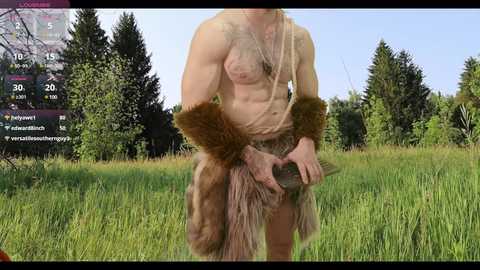 Media: Video of a topless, muscular woman with long blonde hair, wearing fur leggings and arm bands, standing in a lush green field with tall trees in the background.