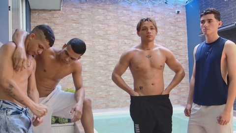 Video of four shirtless young men, one adjusting pants, two leaning on a ledge, and one standing in a modern outdoor setting with a brick wall and pool in the background.