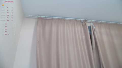 Media: A video of a beige curtain hanging from a metal rod on a white wall, with a calendar featuring \"February\" visible in the upper left corner.
