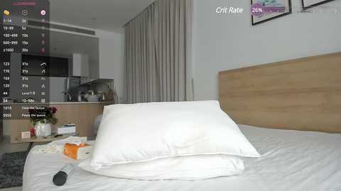 Media: Video of a modern bedroom with a neatly made bed, a wooden headboard, and beige curtains. The room has a minimalist design with a wooden dresser and a TV in the background.