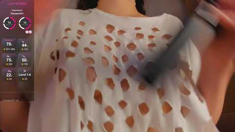 Media: A video of a woman wearing a sheer, white, cut-out blouse with large, irregular holes revealing her breasts, taken from a low angle.