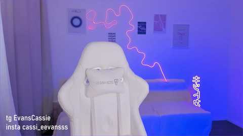 Media: Video of a white gaming chair with a phone attached, surrounded by colorful neon lights and posters in a dimly lit room.