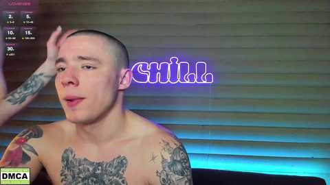 Media: Video of a shirtless, pale-skinned man with a shaved head and numerous tattoos, looking slightly confused, with a neon \"Shut\" sign in the background.
