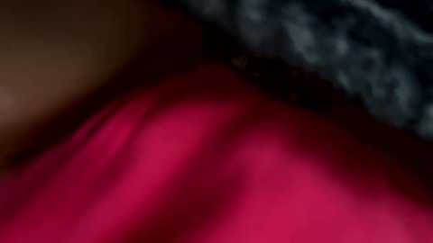 Media: Video of a blurred, close-up shot of a person's red-painted lips and chin, with a black lace garment in the background, creating a sensual and intimate atmosphere.