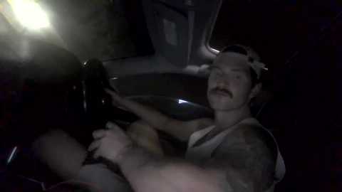 Media: Video of a man with a mustache, wearing a sleeveless tank top, driving a car at night, with dim lighting, and a blurred figure in the background.