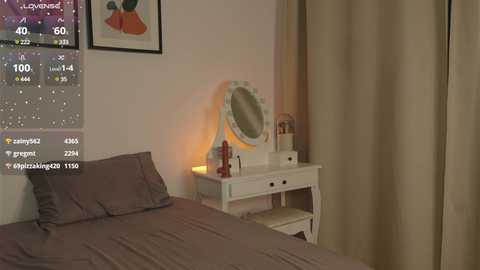 Media: Video of a cozy bedroom with a white vanity table, mirror, and a beige curtain. A gray bed with pillows is visible on the left.
