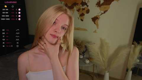 Media: A young, fair-skinned, blonde woman with shoulder-length hair sits in a dimly-lit room, wearing a white spaghetti-strap top, with a live-streaming interface in the background.