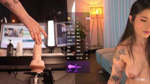 Media: A VR scene shows a topless woman with long dark hair and tattoos, holding a large realistic dildo. The background features a dimly lit room with a computer and a lamp.
