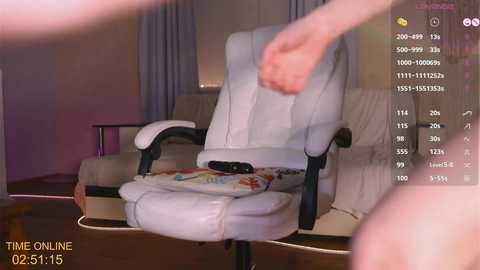 Media: A video showing a person sitting on a beige leather office chair, wearing a white shirt, in a dimly lit room with a window and curtains. The image is marked with a timestamp \"02:31:15\" and \"THE ONLINE\" in the bottom left corner.