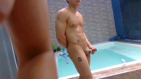 Media: Video of a naked, muscular, light-skinned Asian man with a circumcised penis, standing by an indoor pool with a tiled wall and blue padding.