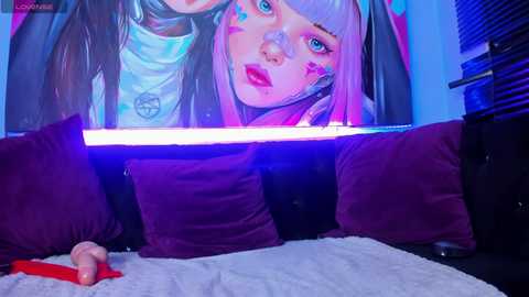 Media: Video of a person with pink hair and face paint, lying on a bed with purple pillows and a white blanket, under a neon-lit poster of a woman with purple hair and red lipstick.