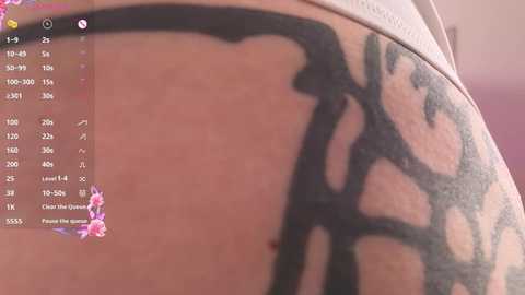 Close-up video of a person's thigh with a large black tribal tattoo, partially covered by a white shirt. The tattoo features intricate, flowing designs.
