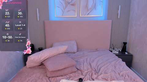 Media: Video of a minimalist bedroom with a pink bed, a black side table, a decorative vase with pink flowers, and a digital clock displaying 22:30.