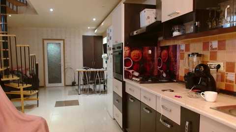 Media: A video of a modern, compact kitchen with white cabinets, black countertops, and a colorful backsplash. The kitchen opens to a dining area with a glass table and chairs.
