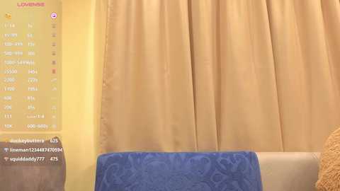 Video of a cozy living room with beige curtains, a blue cushion, and a yellow wall. A digital menu screen in the top left corner displays options for a \"Lumine\" light.
