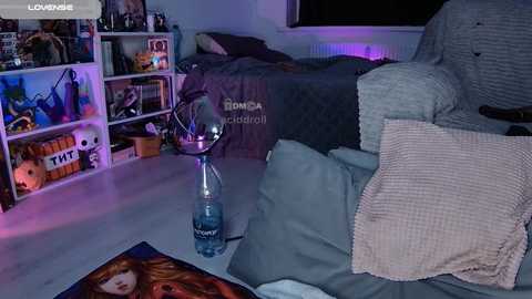 Video of a messy college dorm room with a cluttered bookshelf, a half-made bed, and a water bottle on the floor.