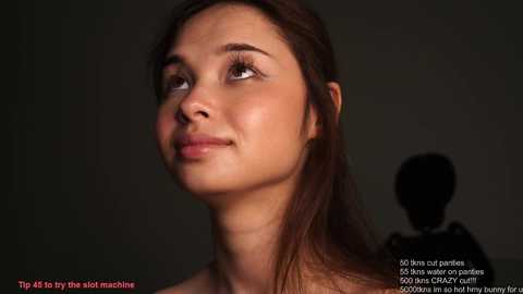 Video of a young woman with light brown skin, dark brown hair, and brown eyes looking upward, set against a dark, blurred background. Text overlays provide makeup tips.