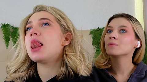 Media: Video of two young women with blonde hair, one with blue eyes sticking out tongue, other with blue eyes, both wearing white earbuds.