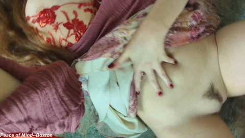A video shows a close-up of a woman's bare, pubic area with red-painted fingernails. Her pale skin is partially covered by a maroon garment.