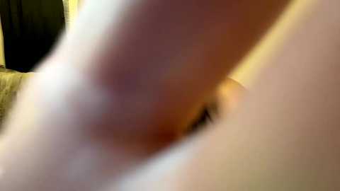 A blurry close-up video of a person's face, likely male, with light skin and a prominent nose, seen from the side. The background is indistinct and out of focus.