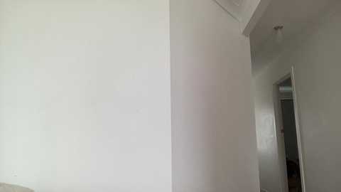 Video of a minimalist, white-walled interior room with a partially open door revealing another room. The lighting is soft, creating a serene and clean atmosphere.