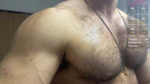 Video of a muscular, hairy male chest, with a thin gold necklace, in a gym setting. Fitness app overlay shows stats like \"chest 40\" and \"arms 30.\
