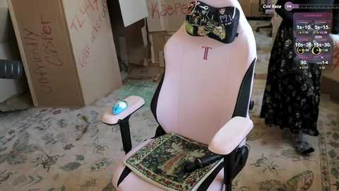 Video of a pink gaming chair with a green and black cloth cover, placed on a patterned carpet in a cluttered room.