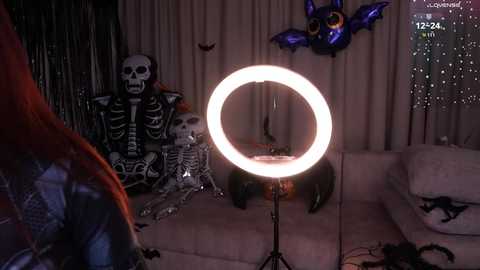 Video of a Halloween-themed living room with a skeleton costume, a glowing ring light, and a bat decoration.