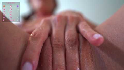 Video of a close-up view of a woman's hand touching her vagina, showing detailed skin texture, with blurred background and a calendar overlay in the corner.