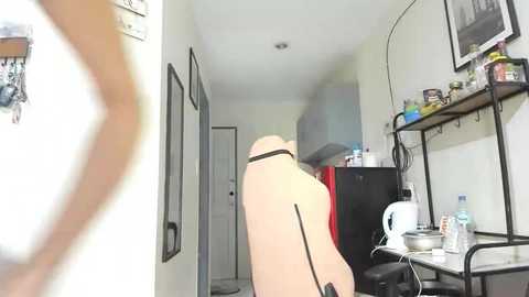 Media: A video of a beige gaming chair in a cluttered room with a fridge, shelves, and a white door in the background.