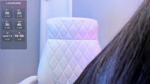 Media: Video of a person with long dark hair, reclining in a quilted white leather recliner with a digital display showing temperature settings.