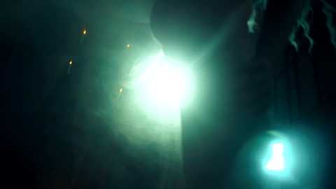 Video of a dense, glowing green fog illuminated by a bright, central white light, with faint yellow lights in the background.