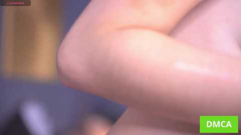 A blurry, close-up video of a nude, light-skinned woman's arm and breast, with a green DMC logo in the bottom right corner.