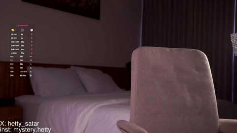 Video of a dimly lit bedroom with a white bed, wooden headboard, and a chair in the foreground. Text in the bottom left reads \"Xx sexy satin just my mystery beauty.\