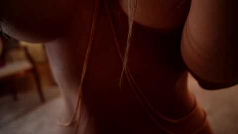 Video of a close-up of a woman's upper torso, wearing a black bra and white lace bralette, with her long blonde hair partially obscuring her face. The background is blurred, suggesting an intimate indoor setting.