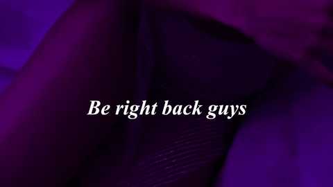 A video with a purple hue features a blurred, dark-skinned hand holding a gun. The text \"Be right back guys\" is centered in white, uppercase letters.