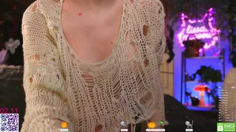 Media: A video of a woman wearing a sheer, beige crochet top with a plunging neckline, revealing her small breasts and nipples. The background features a neon sign and dimly lit room.