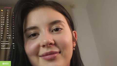 Media: A close-up video of a young Asian woman with straight black hair, fair skin, and a gentle smile. Background includes a streaming screen displaying chat messages.