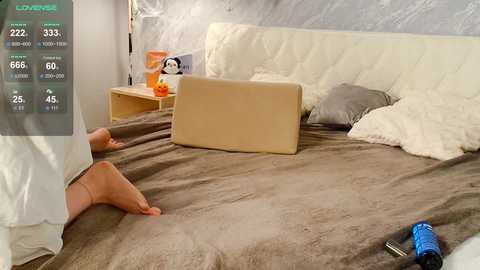 Video of a cozy, minimalist tent bedroom with a beige laptop on a brown blanket, white pillows, and a blue camera.