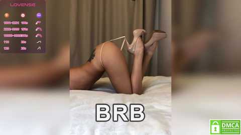A blurred video of a woman in beige lingerie, kneeling on a bed, holding beige high heels, with a \"BBR\" watermark.