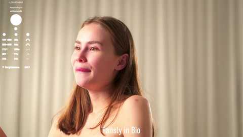 Video of a fair-skinned, light-haired woman with straight hair, wearing a necklace, smiling, against a beige curtain background. Text overlay reads \"Cassandra Biel\" and \"Cassandra Biel 8/22.\