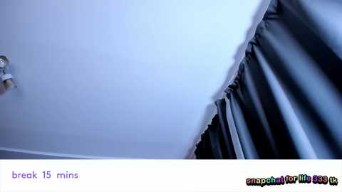 Video of a ceiling with a crack in white paint, with a black curtain partially visible in the right foreground, showcasing a close-up of the damaged area.