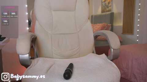 Video of a cozy, beige leather recliner with a black microphone on a white towel, in a softly lit room with a sofa and a framed picture in the background.